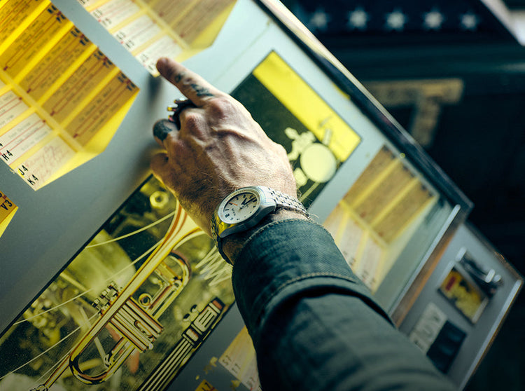 Man wearing a Nixon Echo 38 analog watch and selecting a song on the jukebox