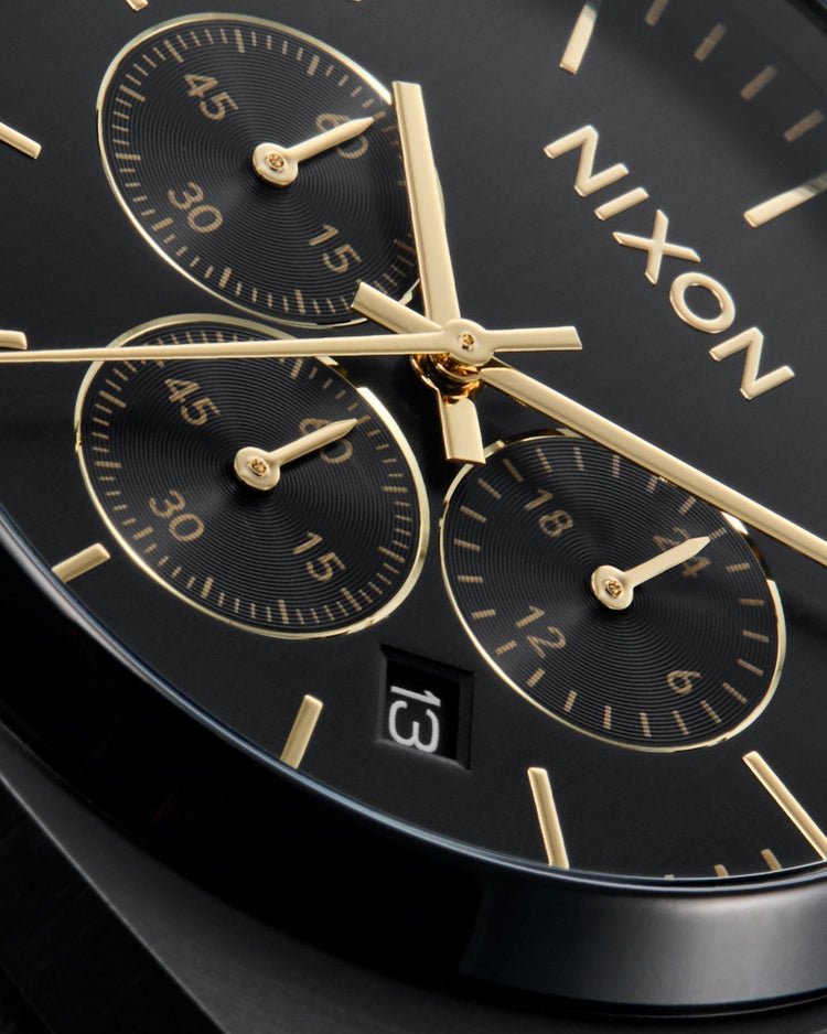 Close up of a dial on a Nixon analog chronograph watch in black and gold